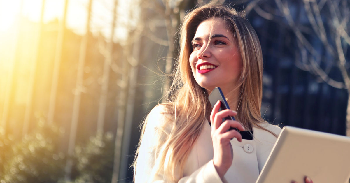 Uma mulher sorrindo com o celular na mão