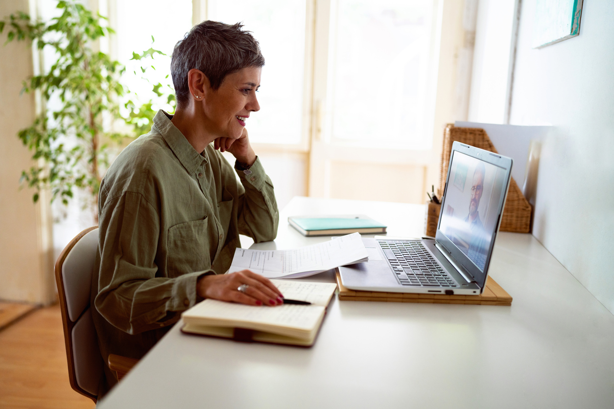 Mulher seguindo cursos on-line em seu laptop em casa.