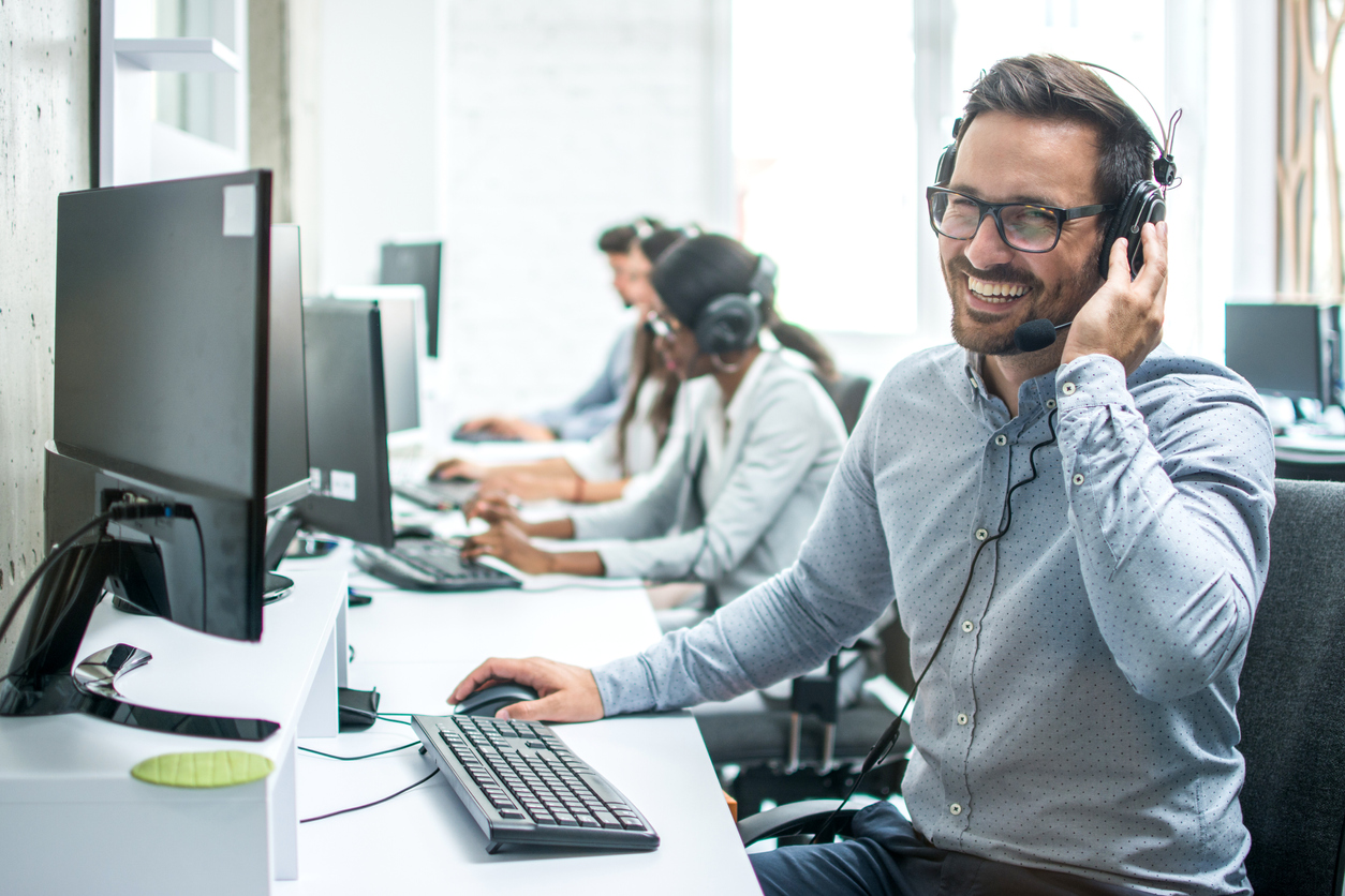 Operador de suporte ao cliente sorridente com fone de ouvido trabalhando em call center.